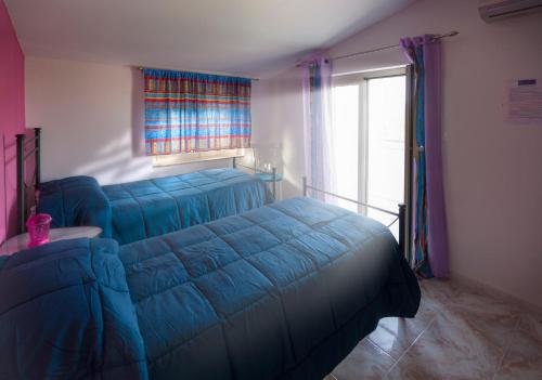 a bedroom with a blue bed and a window at B&B Gàttina in Naso