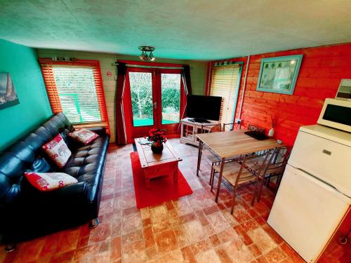a living room with a couch and a table and a refrigerator at Palm Cottage in Redruth