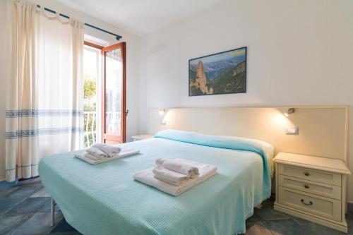 a white bedroom with two towels on a bed at Biriola EcoResort Cala Gonone in Cala Gonone