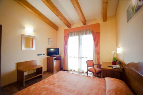 a bedroom with a bed and a desk and a window at Hotel Regio in Rubiera