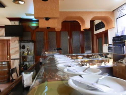 a restaurant with a long counter with white dishes at Hostal San Poul in Consuegra