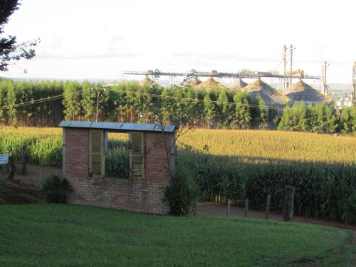 a small brick building in front of a field of corn at Pousada Longe Vista in Tibagi