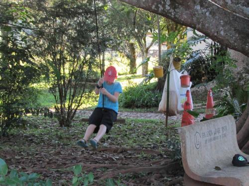 a young boy sitting on a swing in a park at Pousada Longe Vista in Tibagi