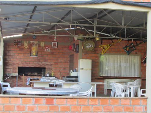 a patio with white tables and chairs and a brick wall at Pousada Longe Vista in Tibagi