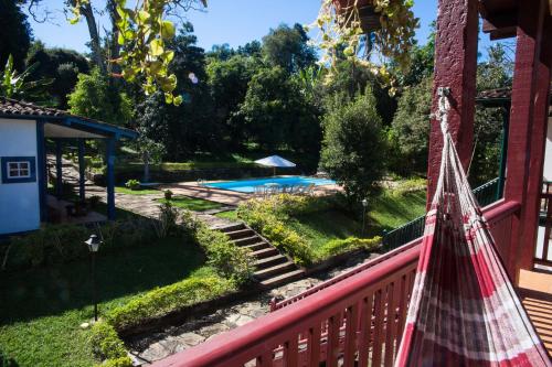 a hammock hanging on the side of a house with a pool at Hotel Solar dos Montes in Santana dos Montes