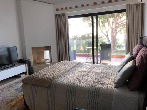 a bedroom with a bed and a tv and a window at Victory Village Club in Quinta do Lago