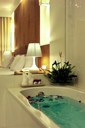 a bathroom with a tub filled with blue water at Princess Seaview Resort & Spa - SHA Plus in Karon Beach