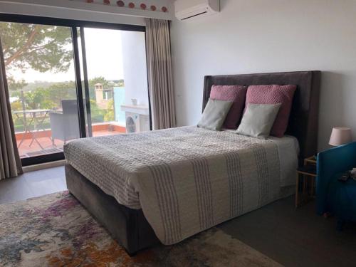 a bedroom with a large bed and a large window at Victory Village Club in Quinta do Lago