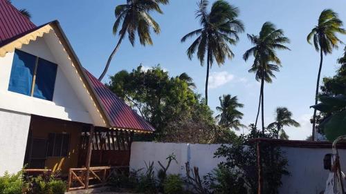 a house with palm trees in the background at Wimbi Cottage in Nungwi