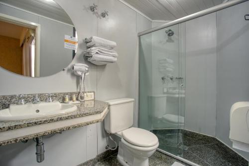 a bathroom with a toilet and a sink and a shower at Roochelle Hotel by Nobile in Curitiba