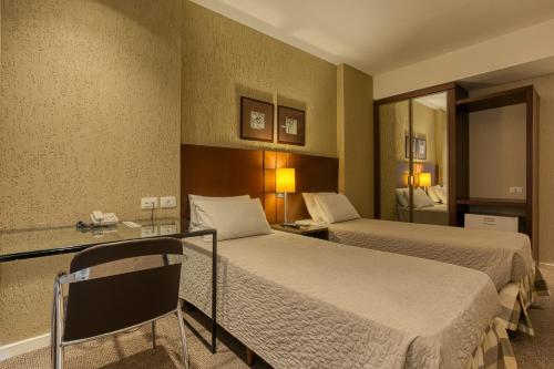 クリチバにあるRoochelle Hotel by Nobileのベッド2台と鏡が備わるホテルルームです。