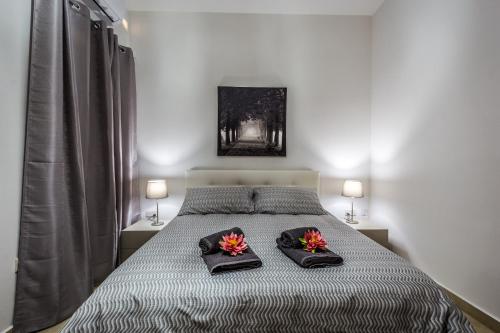 una camera da letto con un letto con due cuscini e fiori di Sunny Modern Apartments a Mellieħa
