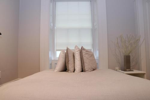 a bed with four pillows in front of a window at Charming & Stylish Studio on Beacon Hill #11 in Boston