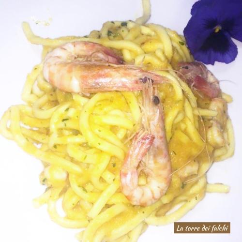 a plate of pasta with shrimp and a purple flower at Hotel Caserta Antica in Caserta