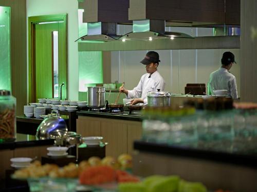 two chefs in a kitchen preparing food in a kitchen at Hotel Santika Palu in Palu