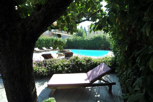 a bench sitting under a tree next to a pool at Residenza Villa Titina in SantʼAgata sui Due Golfi
