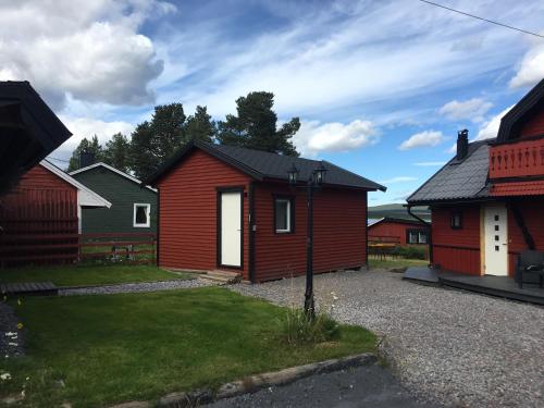 a red house with a white door in a yard at Camp Caroli in Jukkasjärvi