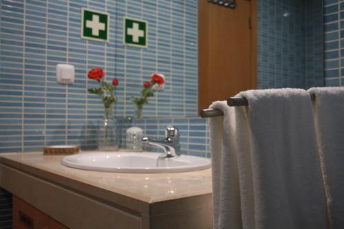 ein Badezimmer mit einem Waschbecken und Blumen an der Wand in der Unterkunft Apartamento com Piscina em Albufeira, Corcovada in Albufeira