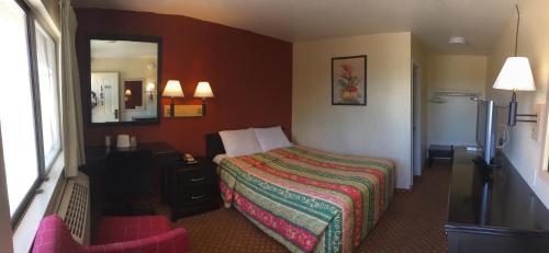 a hotel room with a bed and a mirror at Hilltop Inn & Suites in Victorville