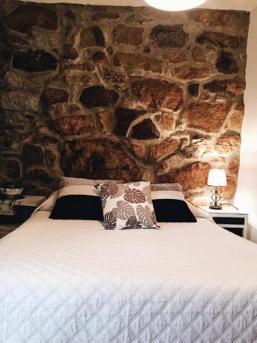 a bedroom with a large bed with a stone wall at Casa da Cris in Cotelo