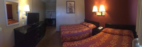 a hotel room with two beds and a mirror at Hilltop Inn & Suites in Victorville