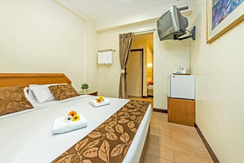 um quarto com uma cama e uma televisão na parede em Hotel 81 Geylang em Singapura
