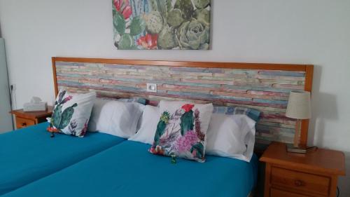 Un dormitorio con una cama azul con almohadas y una pared de ladrillo en Estudio La Calzada, en Villaverde