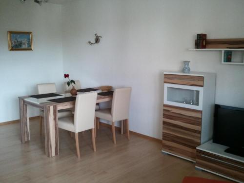 a dining room table with white chairs and a television at Ferienwohnung Sonne-Stadtrand Dresden in Moritzburg