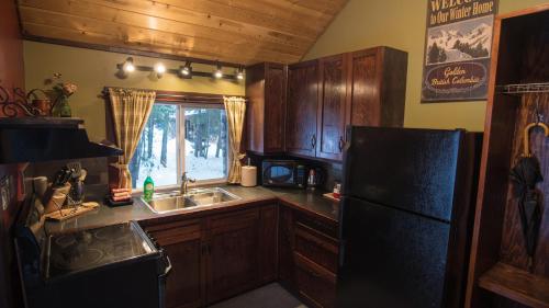 a kitchen with a black refrigerator and a sink at Cedar House Restaurant & Chalets in Golden