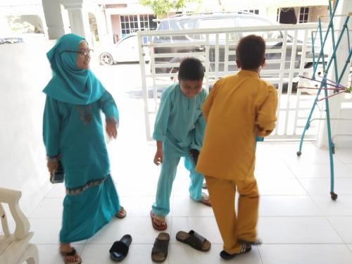 um grupo de três crianças ao lado de um homem em Anis Homestay Kuala Perlis em Kuala Perlis