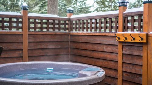 a wooden fence with a hot tub in a yard at Cedar House Restaurant & Chalets in Golden