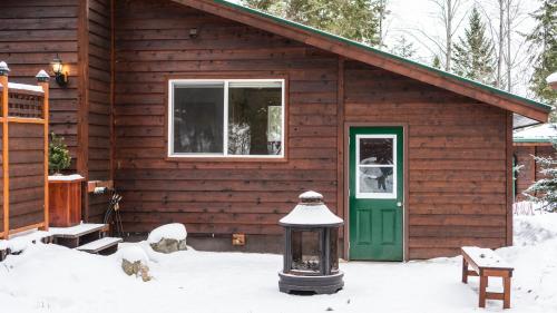 a log cabin with a green door in the snow at Cedar House Restaurant & Chalets in Golden