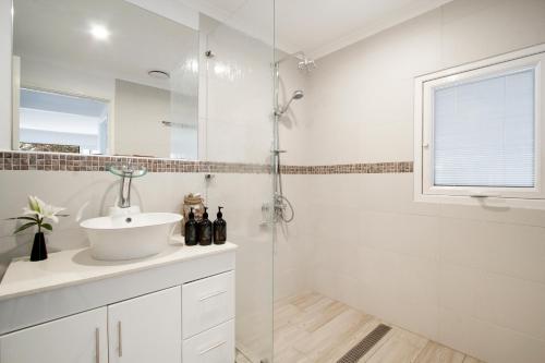 uma casa de banho branca com um lavatório e um chuveiro em The Jetty em Lancelin