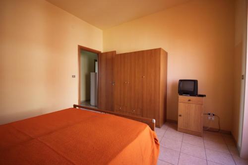 Schlafzimmer mit einem Bett und einem Schrank mit einem TV in der Unterkunft Appartamenti San Foca in San Foca