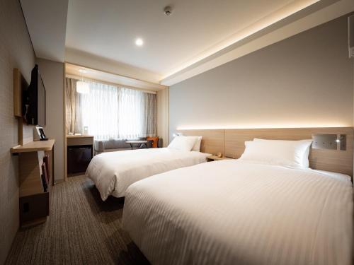 a hotel room with two beds and a window at Nishitetsu Hotel Croom Nagoya in Nagoya