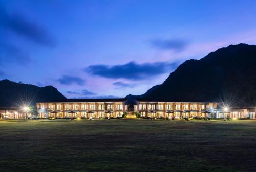 a large building at night with mountains in the background at La Isla Pranburi Beach Resort in Sam Roi Yot
