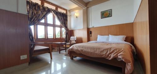 a bedroom with a bed and a desk and a window at Hotel The Oak in Tawang