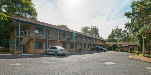 a building with two cars parked in a parking lot at Country 2 Coast Motor Inn Coffs Harbour in Coffs Harbour