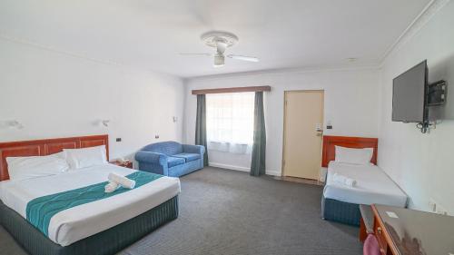 a hotel room with a bed and a chair at Country 2 Coast Motor Inn Coffs Harbour in Coffs Harbour