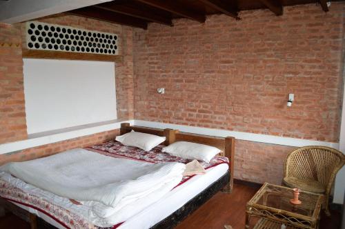 a bed in a room with a brick wall at Hotel At The End Of The Universe in Nagarkot