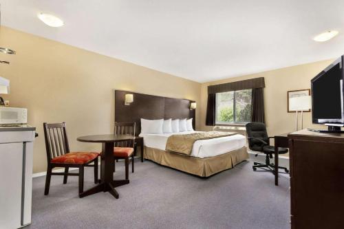 a hotel room with a bed and a table and chairs at Super 8 by Wyndham West Kelowna BC in West Kelowna