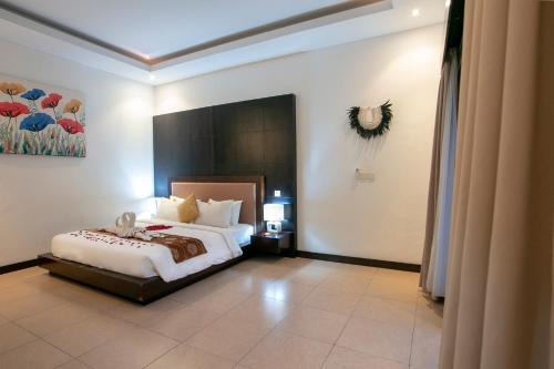 a bedroom with a bed and a painting on the wall at Villa Raka Managed by Manara in Legian