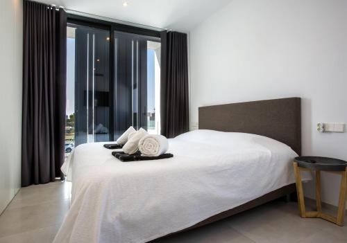 um quarto com uma cama com lençóis brancos e janelas em Clem em Calpe