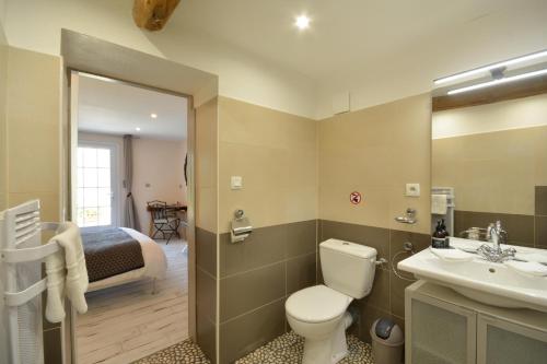a bathroom with a toilet and a sink and a bed at chambres d hotes Le Mas Julien piscine chauffée adult only in Orange