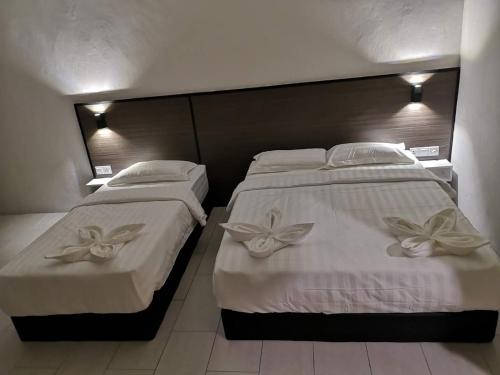 two beds in a hotel room with white sheets at Luna Guesthouse 露娜旅馆 in Semporna