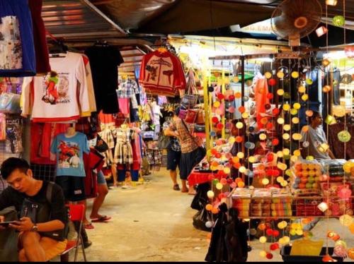 a store with people walking around a market with merchandise at By The Sea Beach Front Apartment in Batu Ferringhi