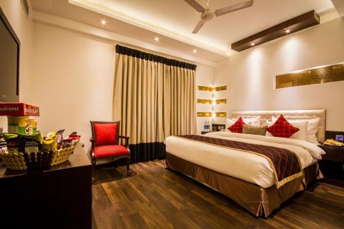 a hotel room with a bed and a red chair at Hotel Grand Godwin - Free Airport Pick-Up in New Delhi