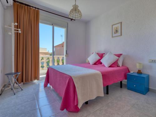 um quarto com uma cama rosa e uma grande janela em Holiday Home Campo Olivar by Interhome em Els Poblets