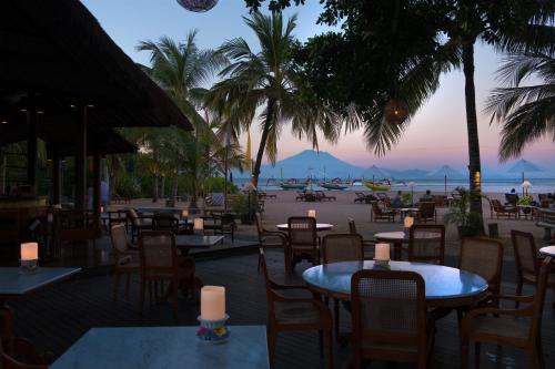 a restaurant with tables and chairs with a view of the beach at Tandjung Sari Hotel in Sanur