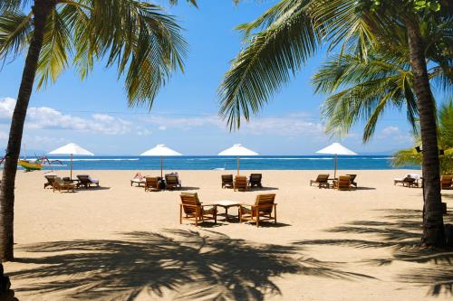 a beach with chairs and umbrellas and the ocean at Tandjung Sari Hotel in Sanur
